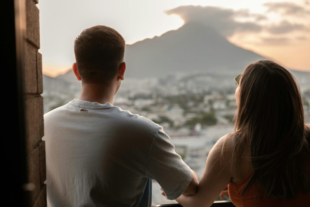 A young couple shares a romantic moment, overlooking Monterrey's cityscape and mountains at sunset.